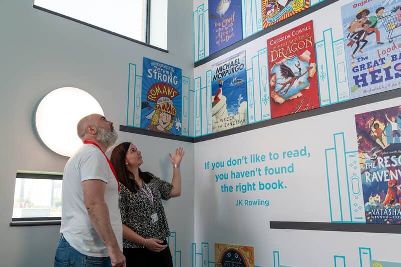 An image of two people looking at indoor posters of different books.